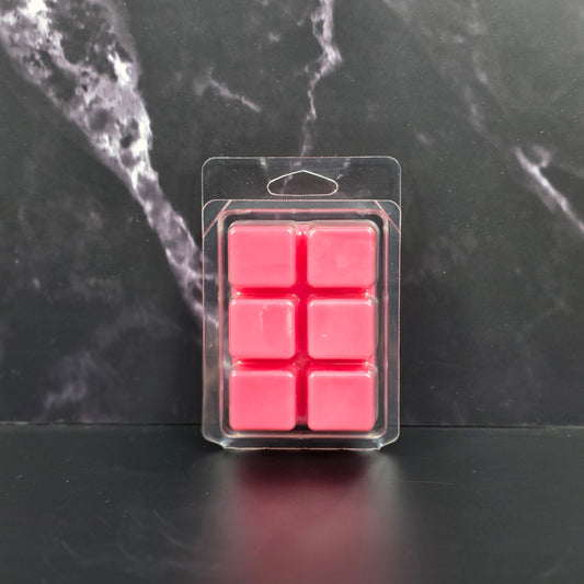 Pack of six pink wax melts in clear packaging on a black marble surface