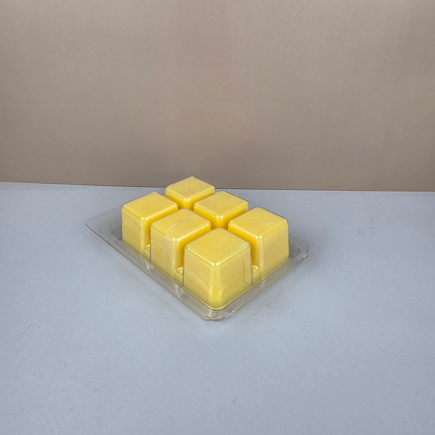 Pack of yellow wax cubes in a clear plastic packaging on a gray background