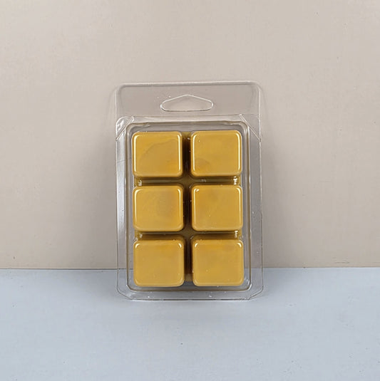 Pack of six yellow wax melts in a clear plastic packaging on a light gray background