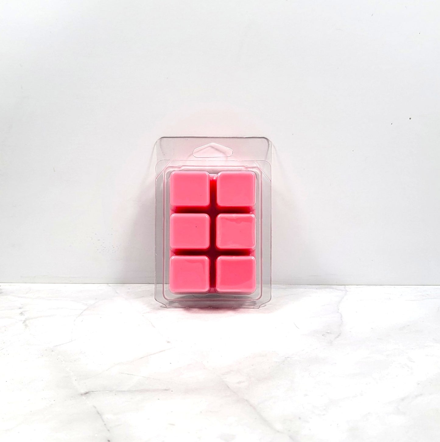 Pink wax melts in a clear plastic packaging on a white background