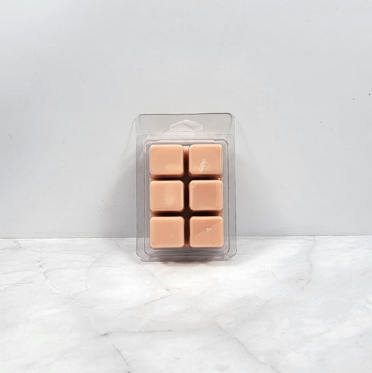 Pack of tan-colored wax melts in clear packaging on a white marble surface.