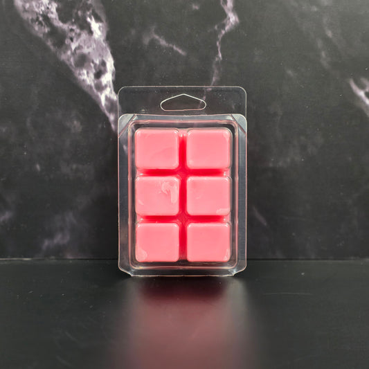 Pack of pink wax melts in clear packaging on a dark marble surface