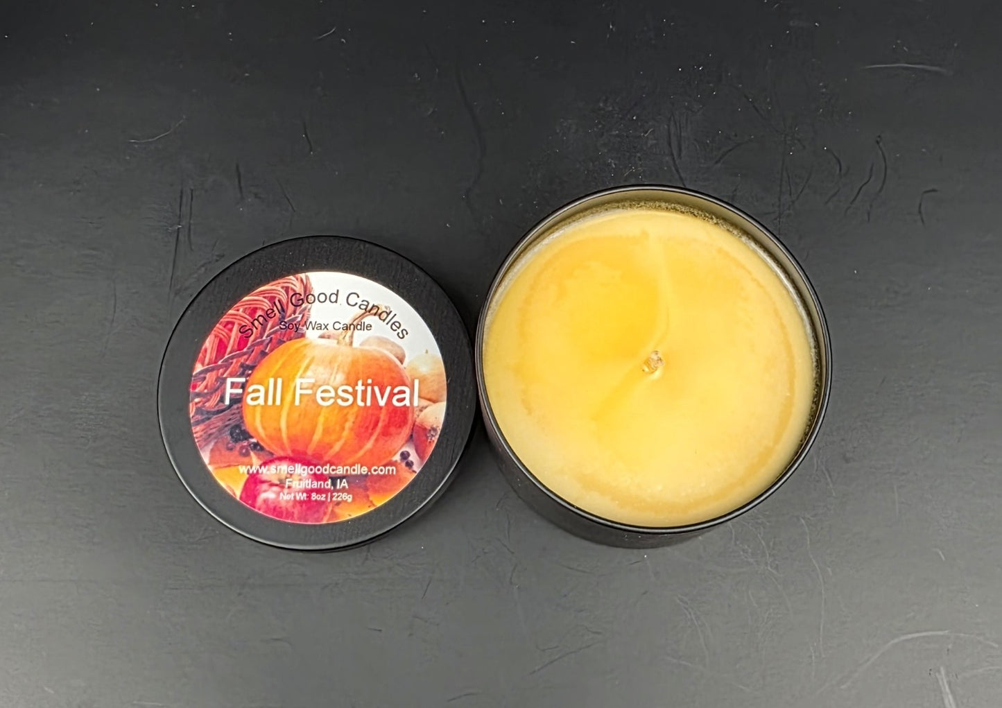 Candle in a tin with a decorative label on a dark surface