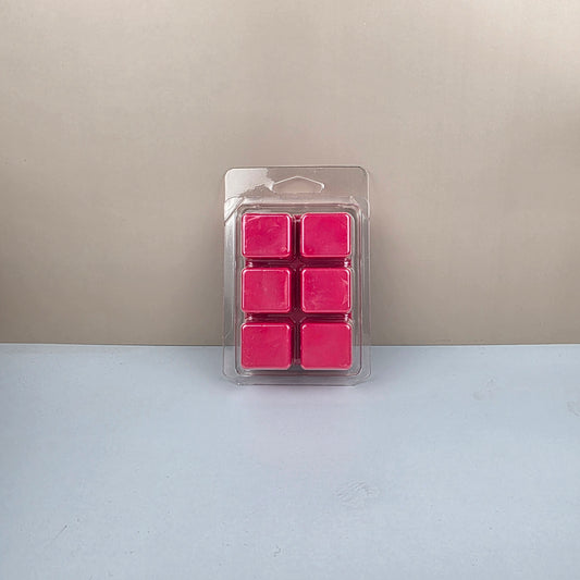 Pack of pink wax cubes in clear plastic packaging on a beige and white background