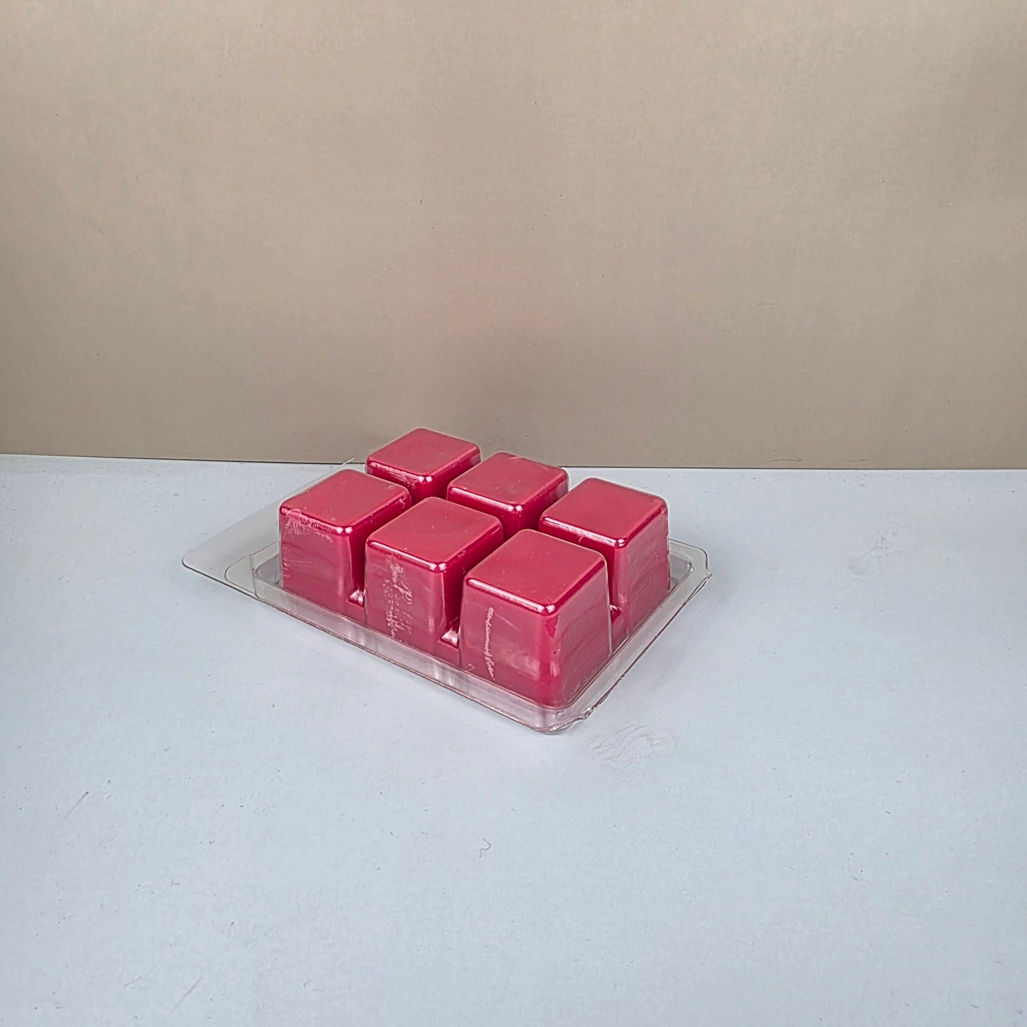 Pink wax melts in a clear mold on a white surface.
