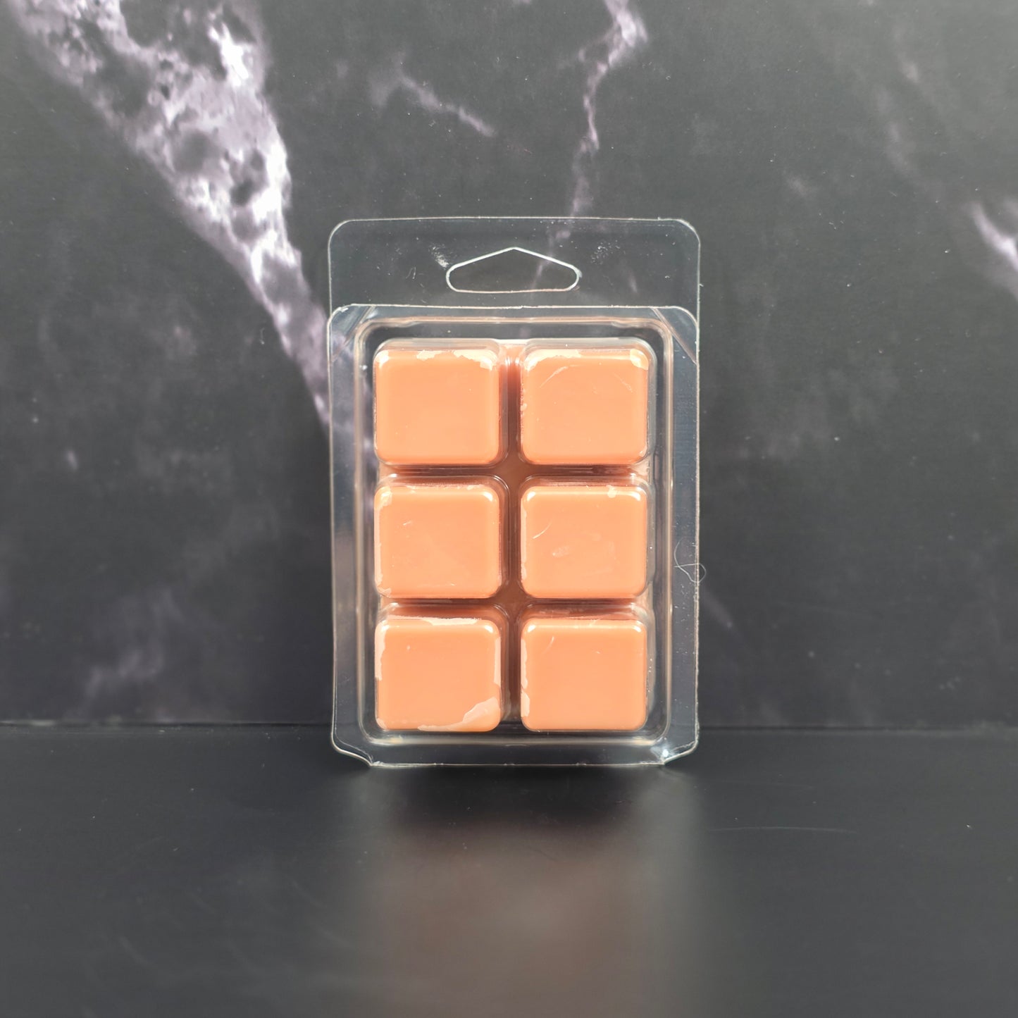 Six-pack of brown Hot Cocoa scented soy wax melts displayed on a black marble background.