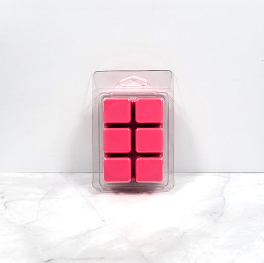 Kisses and Dreams wax melt beside a lit warmer in a cozy bedroom setting