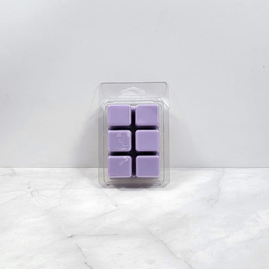 Pack of purple wax melts in clear packaging on a white marble surface