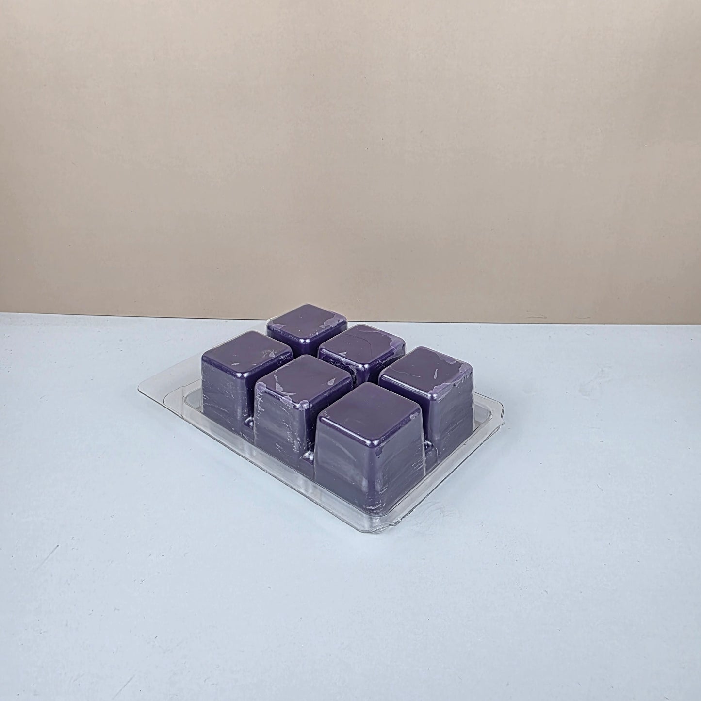 Purple wax cubes in a transparent holder on a white background