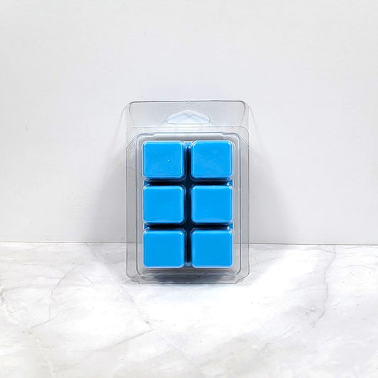 Earth-toned wax melt cubes beside moss, bark, and sandalwood