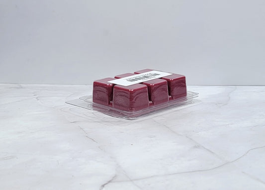 Dark-themed wax melt with berries and plum on a velvet backdrop