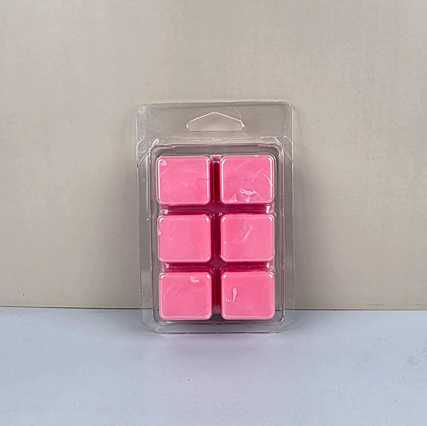 Pack of pink wax melts in clear packaging on a light gray background