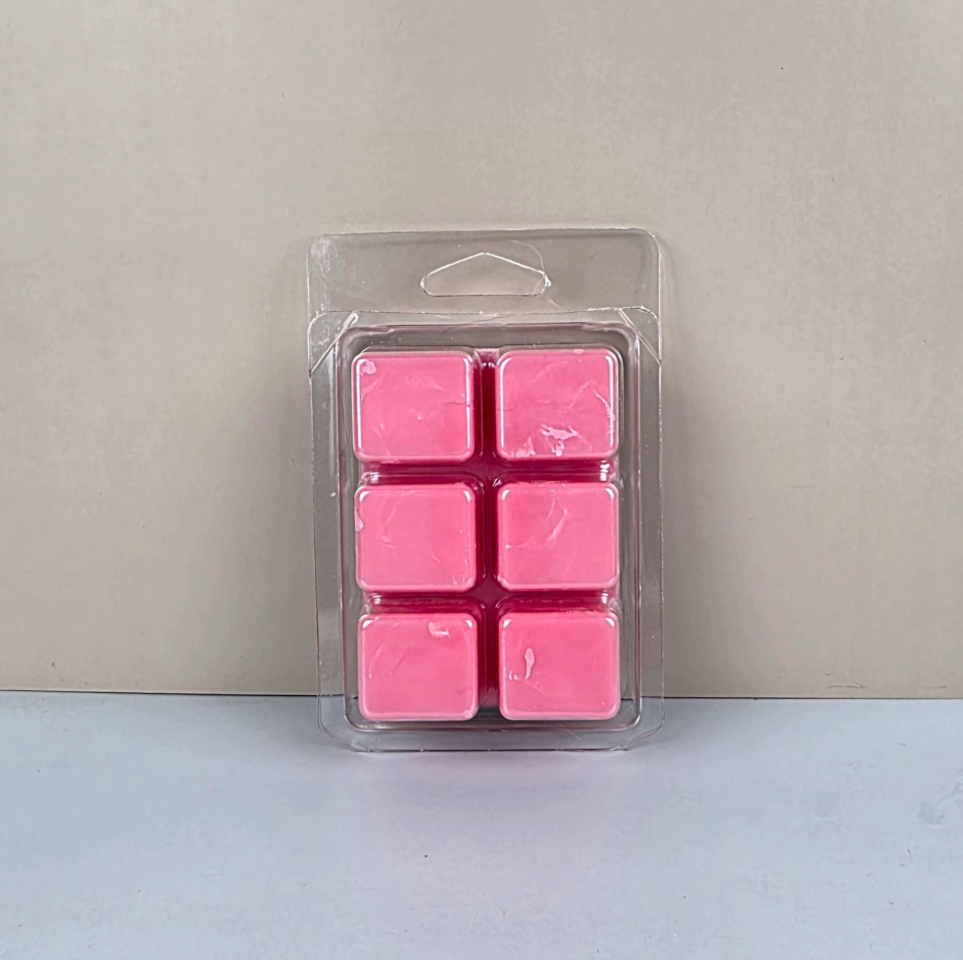 Pack of pink wax melts in clear packaging on a light gray background