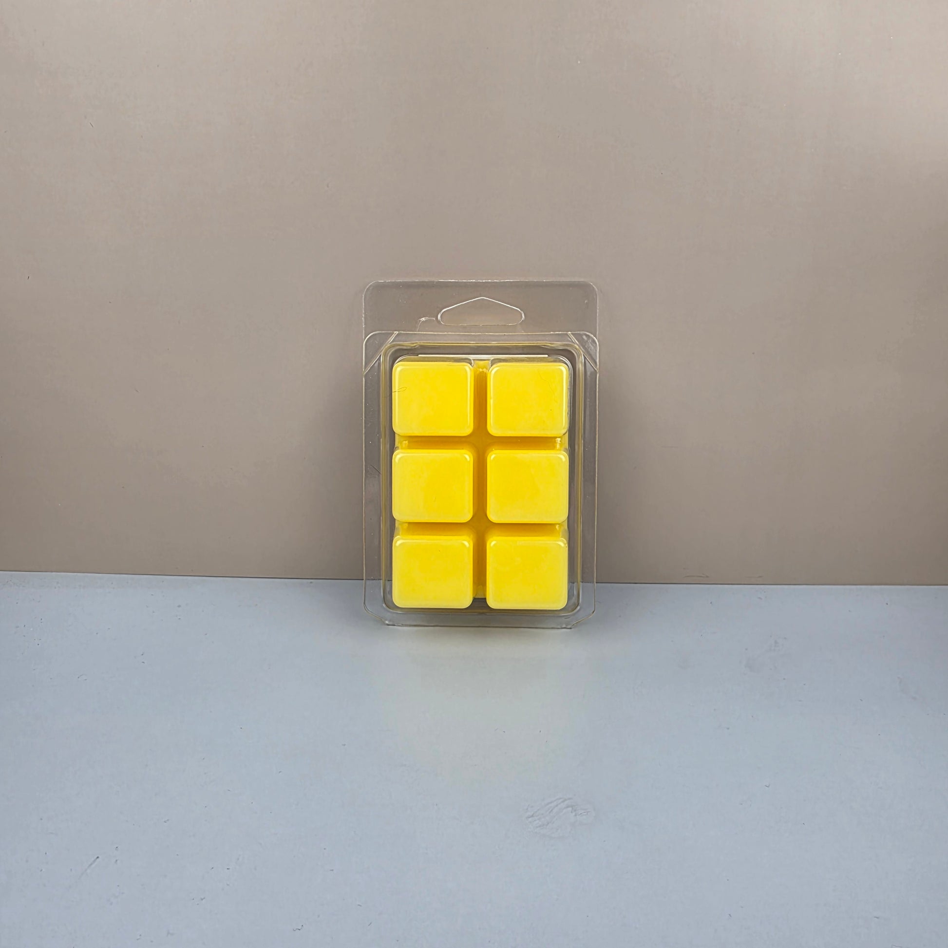 Pack of six yellow wax cubes in clear packaging on a neutral background