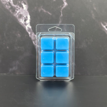 Clear plastic packaging with six blue square items on a dark marble surface