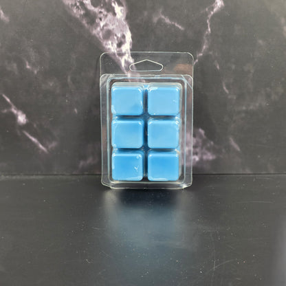 Pack of blue wax melts in clear packaging on a dark marble surface