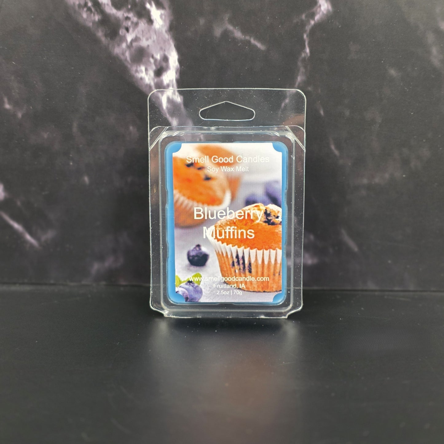 Packaged blueberry muffin wax melts on a dark surface with a marble background