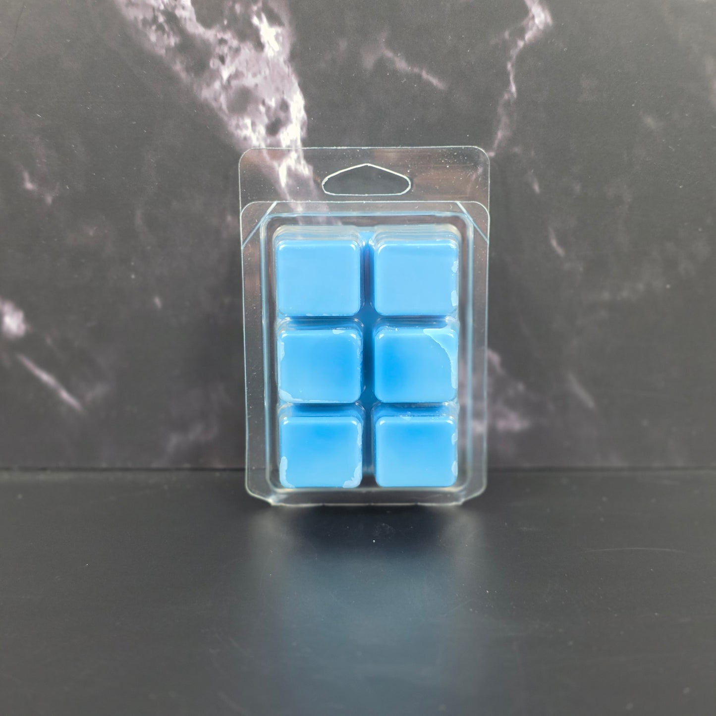 Pack of blue wax melts on a dark marble surface