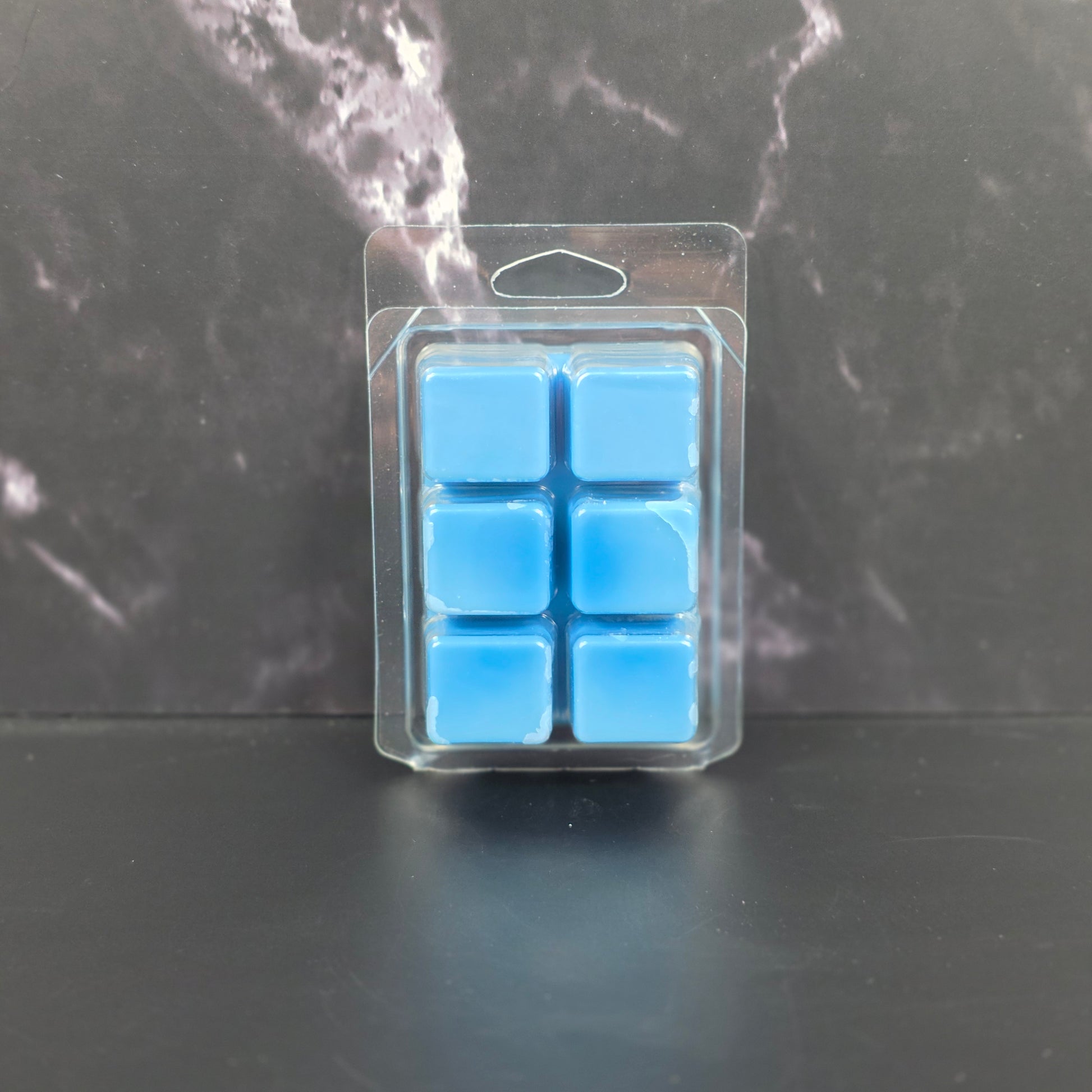 Pack of blue wax melts on a dark marble surface