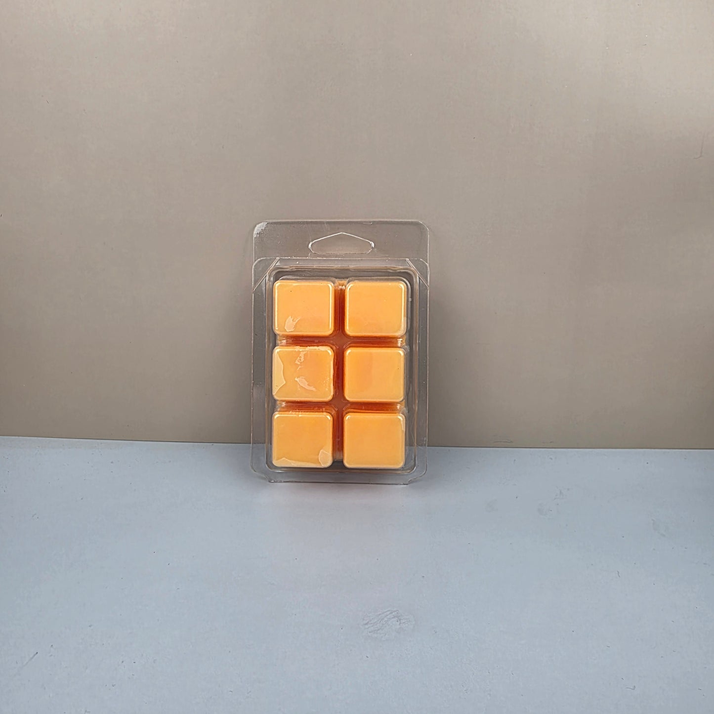 Pack of yellow wax cubes in clear plastic packaging on a gray background