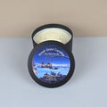 Soy wax candle in a black container with a 'Christmas Memories' label on a white surface.