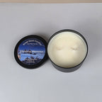 Candle in a black container with a label on a light gray background