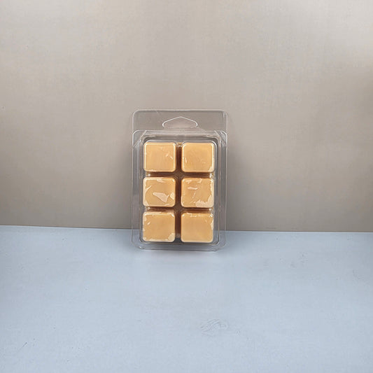 Pack of six gold-colored wax melts in a clear plastic packaging against a neutral background