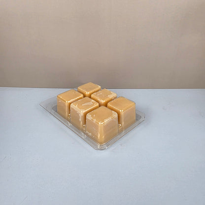Beige wax melt cubes in a clear plastic packaging on a light gray background