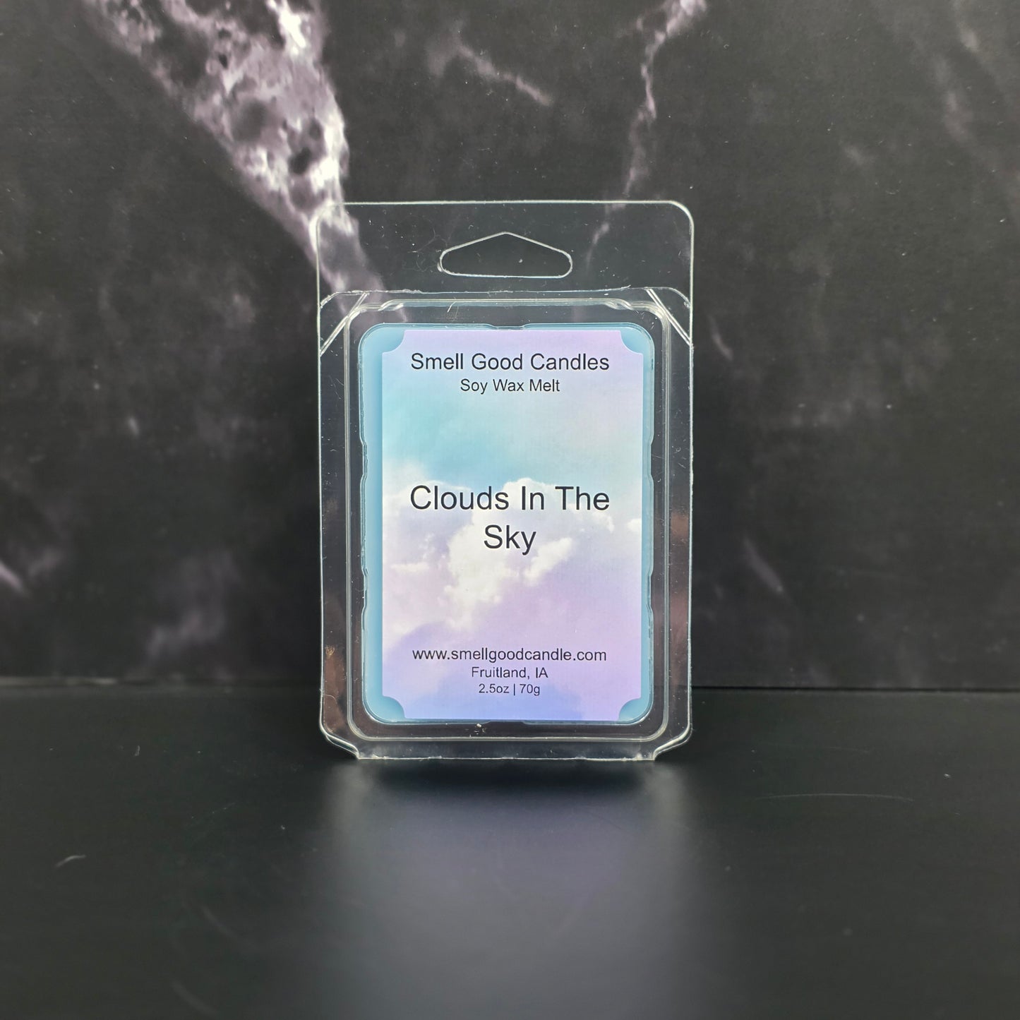 Wax melt packaging labeled 'Clouds In The Sky' on a dark marble surface