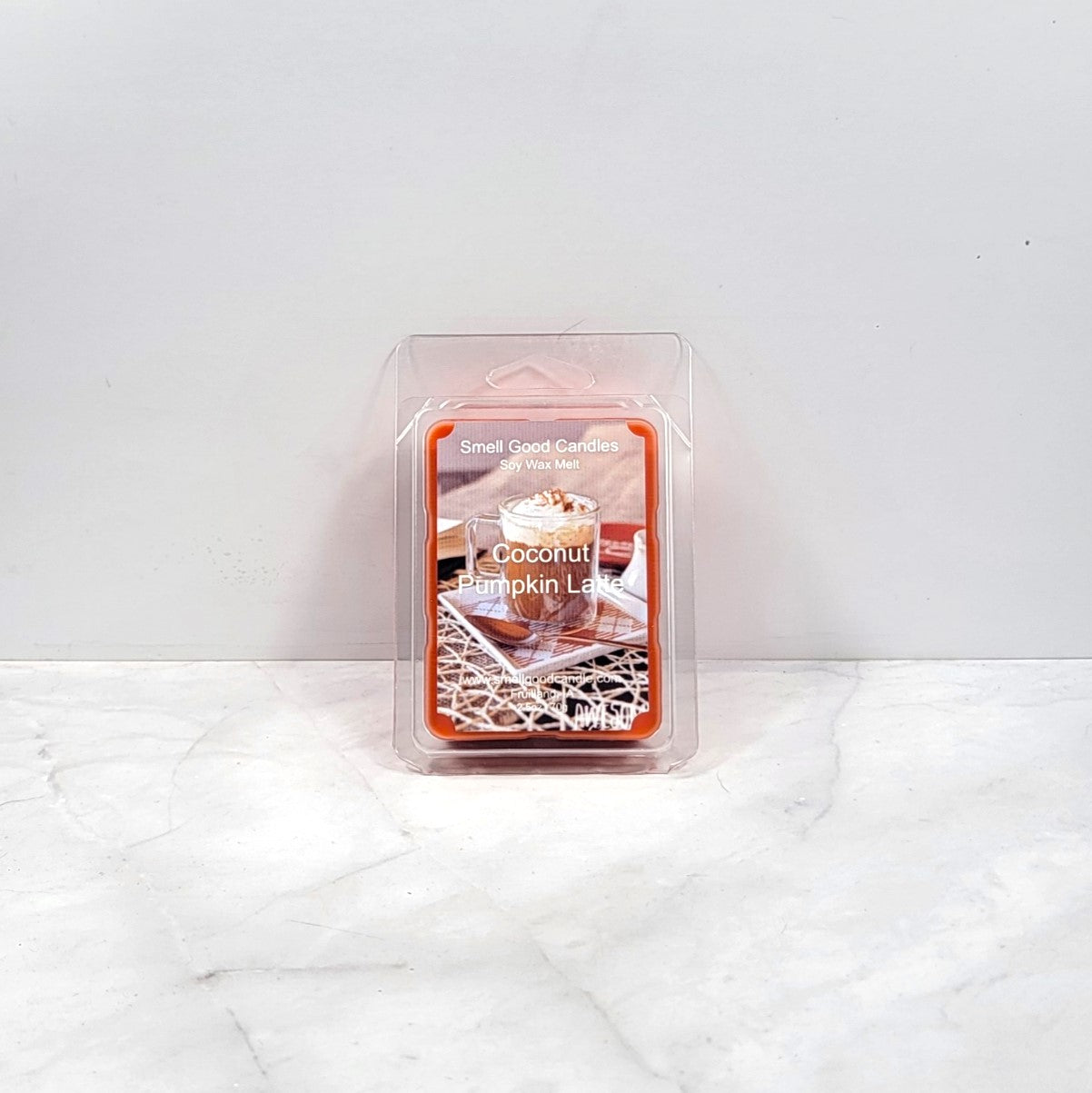 Packaged coconut pumpkin latte candle on a white marble surface