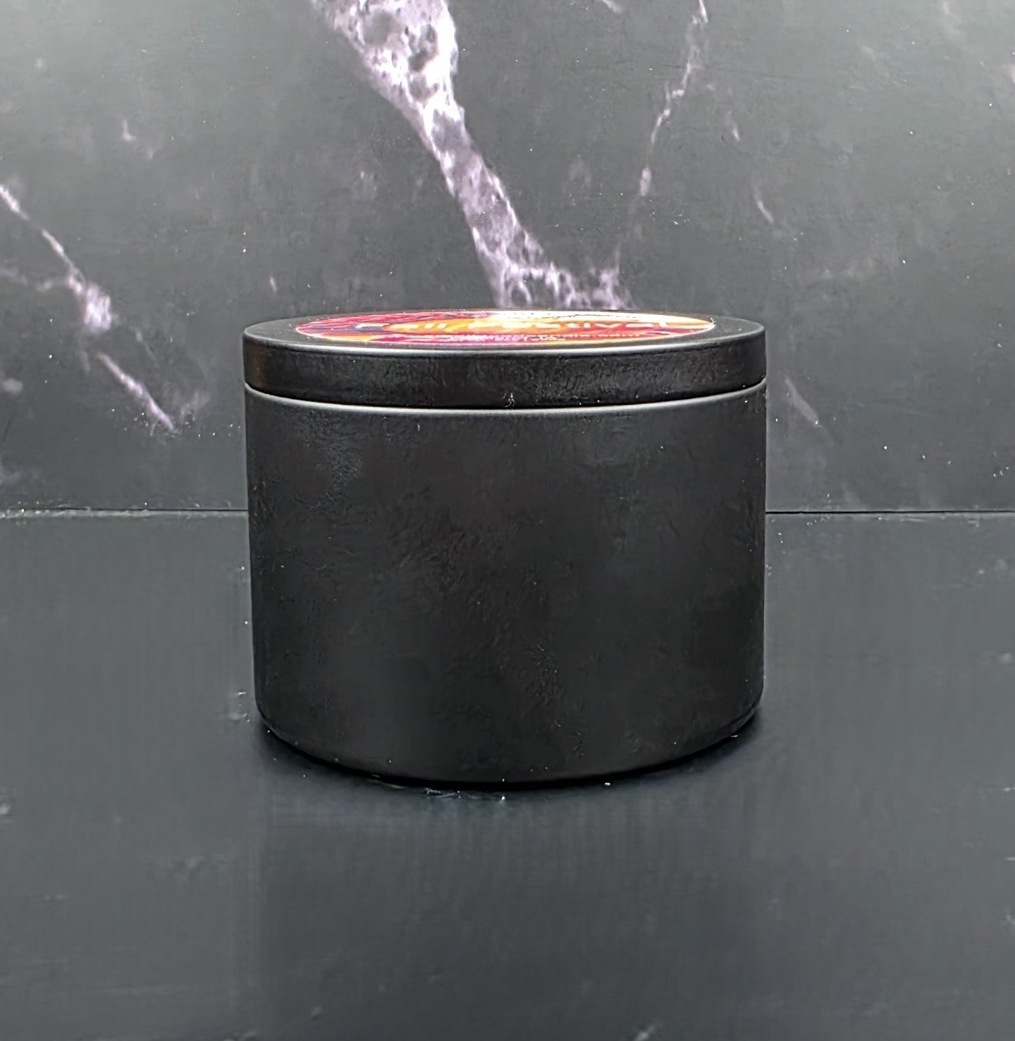 Black cylindrical container with a lid on a dark marble surface