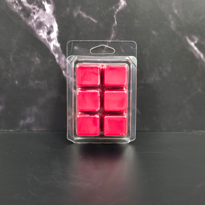 Pack of six red wax melts in clear packaging on a dark marble surface