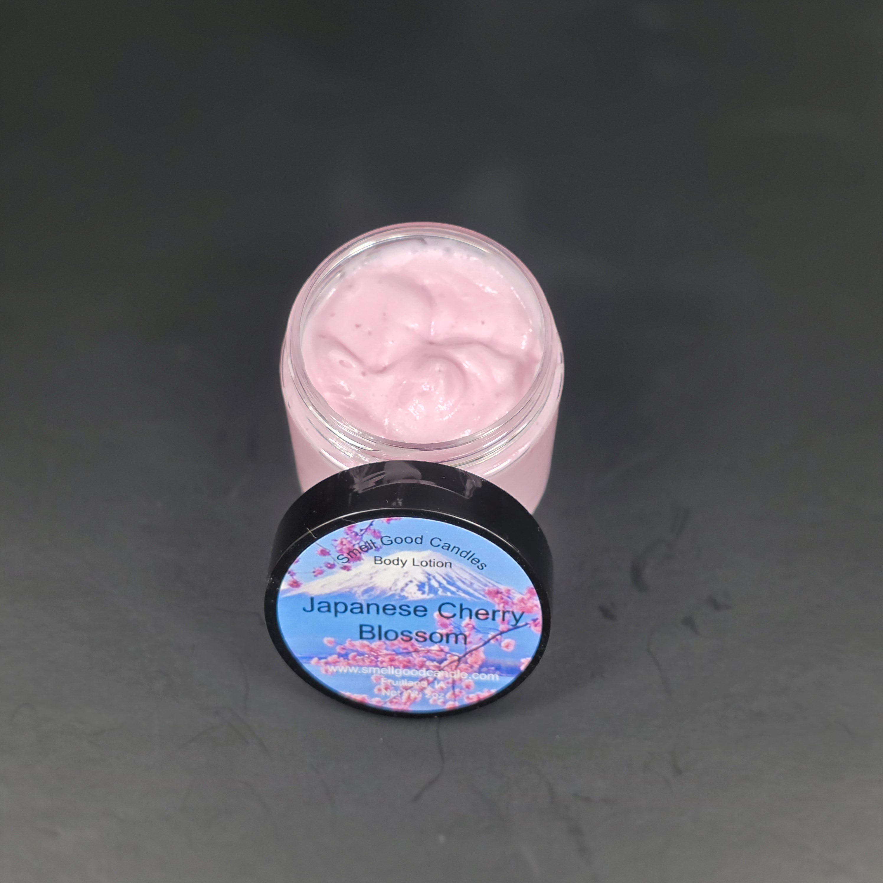 Pink cream in a jar with a decorative lid on a dark surface