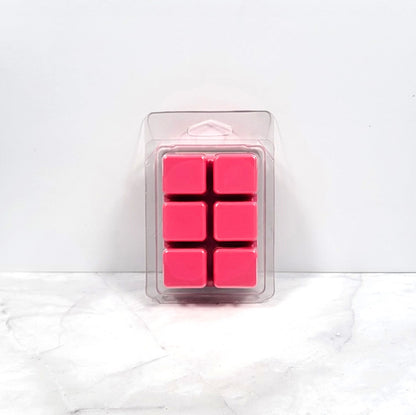 Kisses and Dreams wax melt beside a lit warmer in a cozy bedroom setting