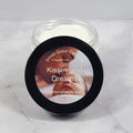 Jar of 'Kisses and Dreams' whipped body lotion with a baby image on the label against a white marble background.