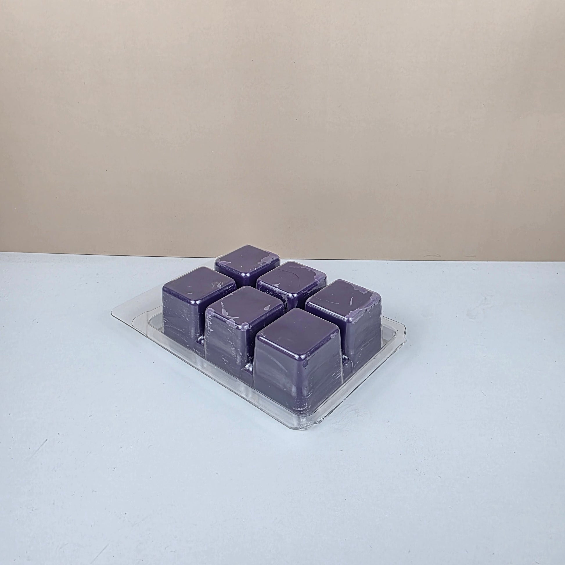 Purple wax cubes in a transparent holder on a white background
