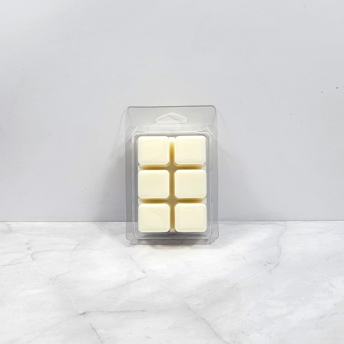 Packaged wax melts on a marble surface with a light gray background