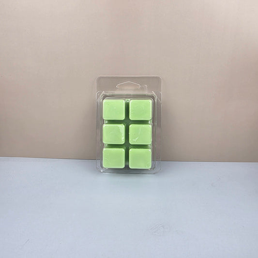 Pack of green wax cubes in a clear plastic packaging on a beige and white background
