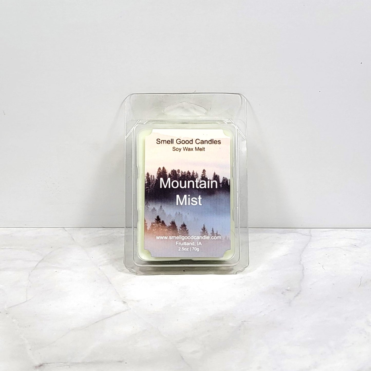 Mountain Mist soy wax melt surrounded by moss, pinecones, and greenery