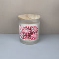 Frosted glass candle jar with wooden lid and peppermint-themed label on a neutral background
