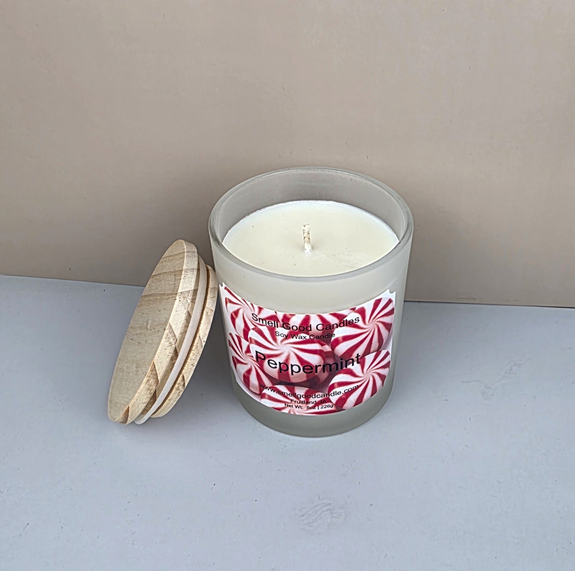 Candle in a glass jar with a peppermint label on a neutral background