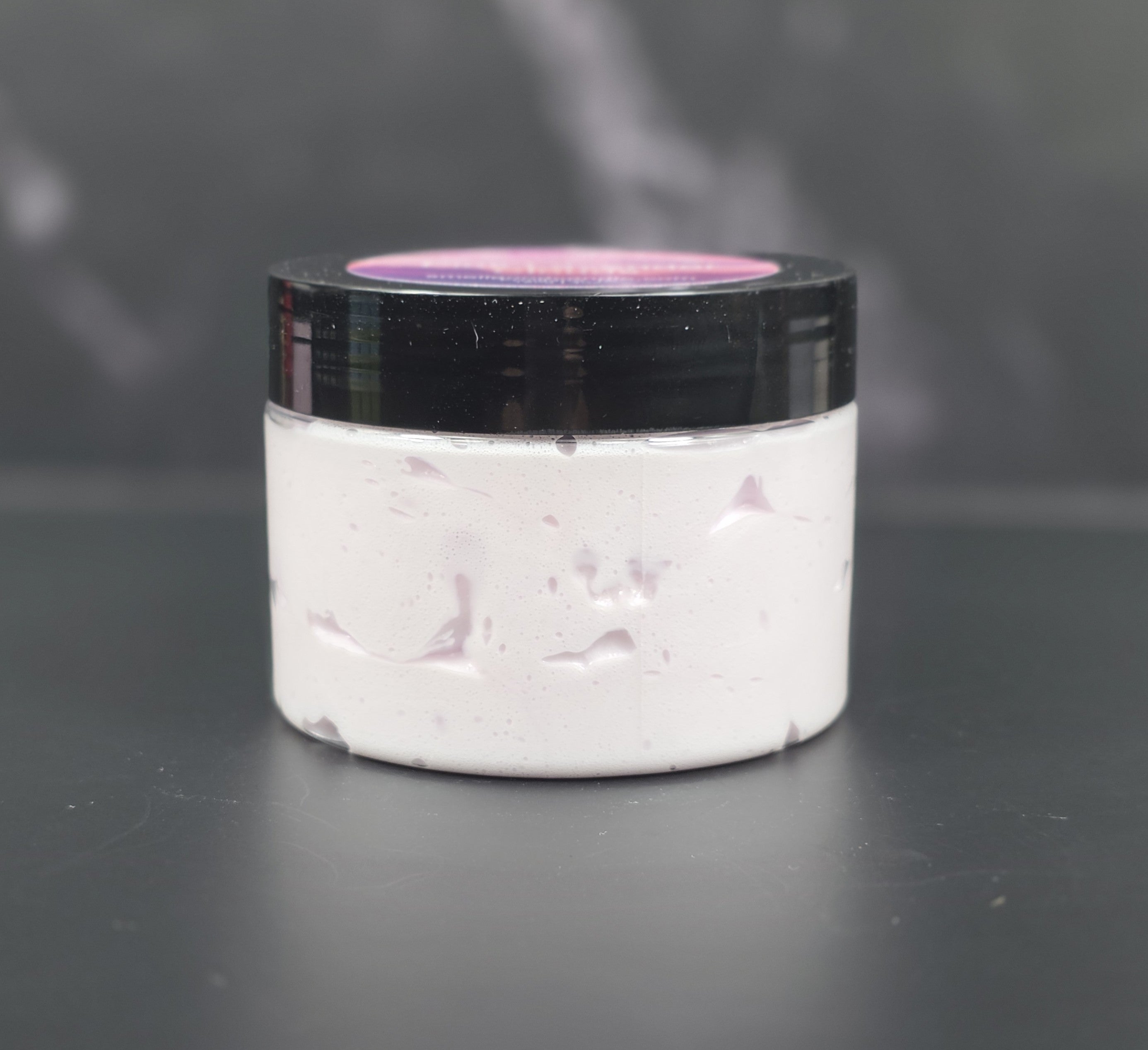 Whipped body lotion with lavender, pink sugar, and amber fragrance in a clear jar with a black lid