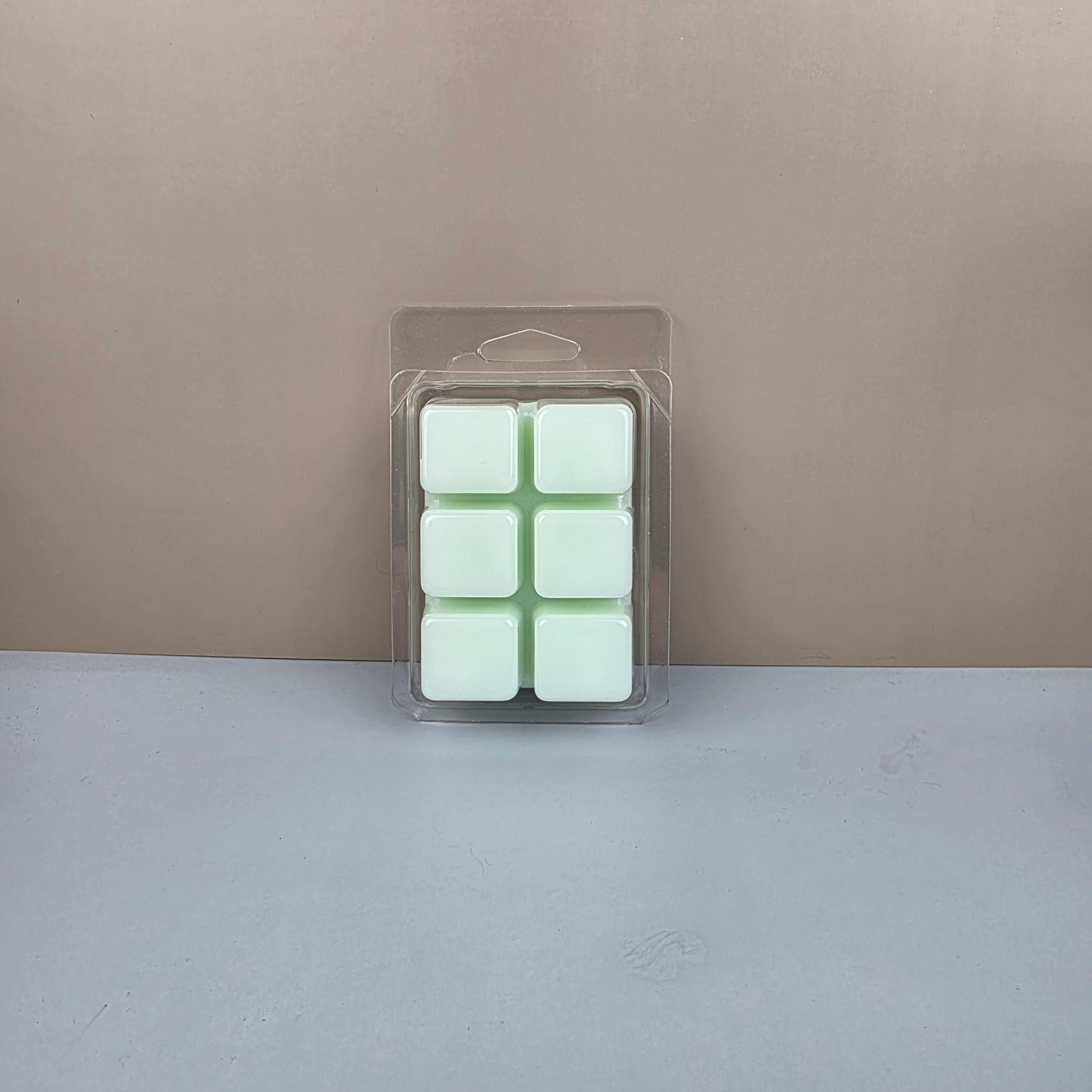Packaged green wax melts on a neutral background