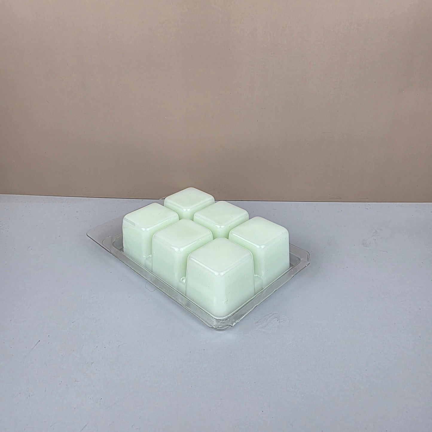 Hexagonal wax melts in a clear container on a light gray background