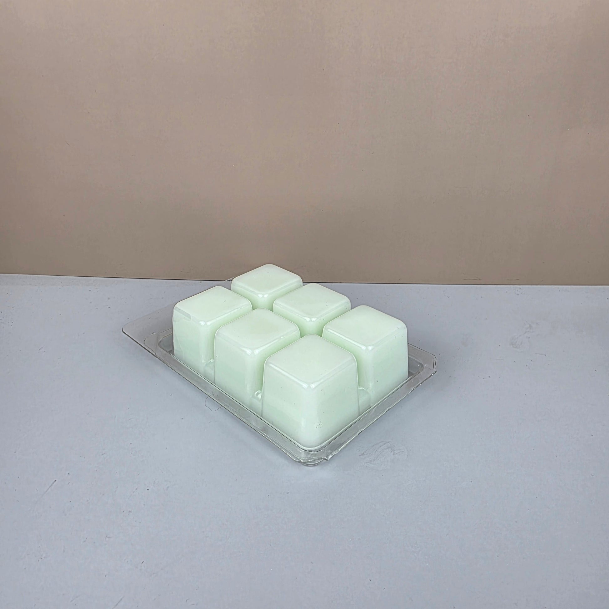 Hexagonal wax melts in a clear container on a light gray background
