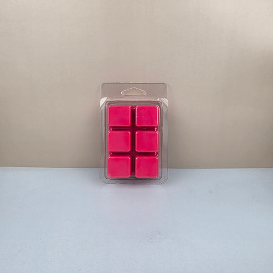 Pack of pink wax melts in a clear plastic packaging on a beige and white background