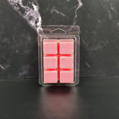 Pack of pink wax melts in clear packaging on a dark marble background