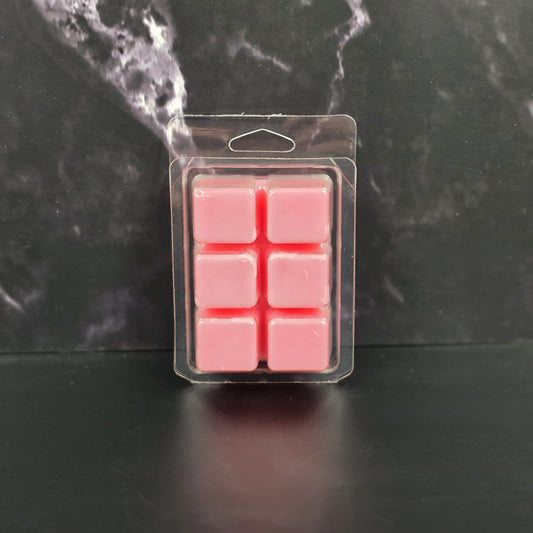 Pack of pink wax melts in clear packaging on a dark marble background