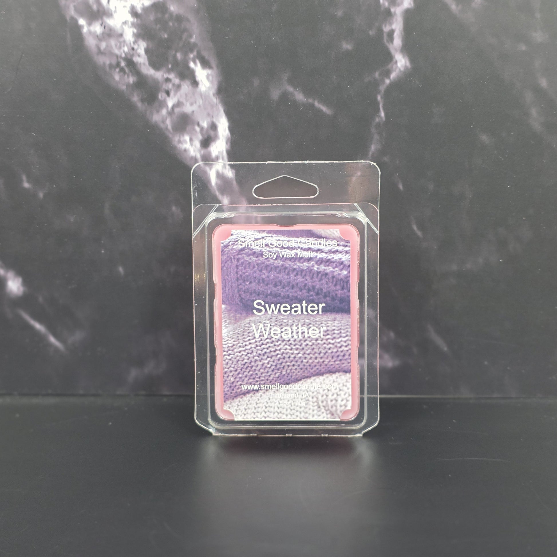 Packaged sweater-themed wax melt on a dark marble background