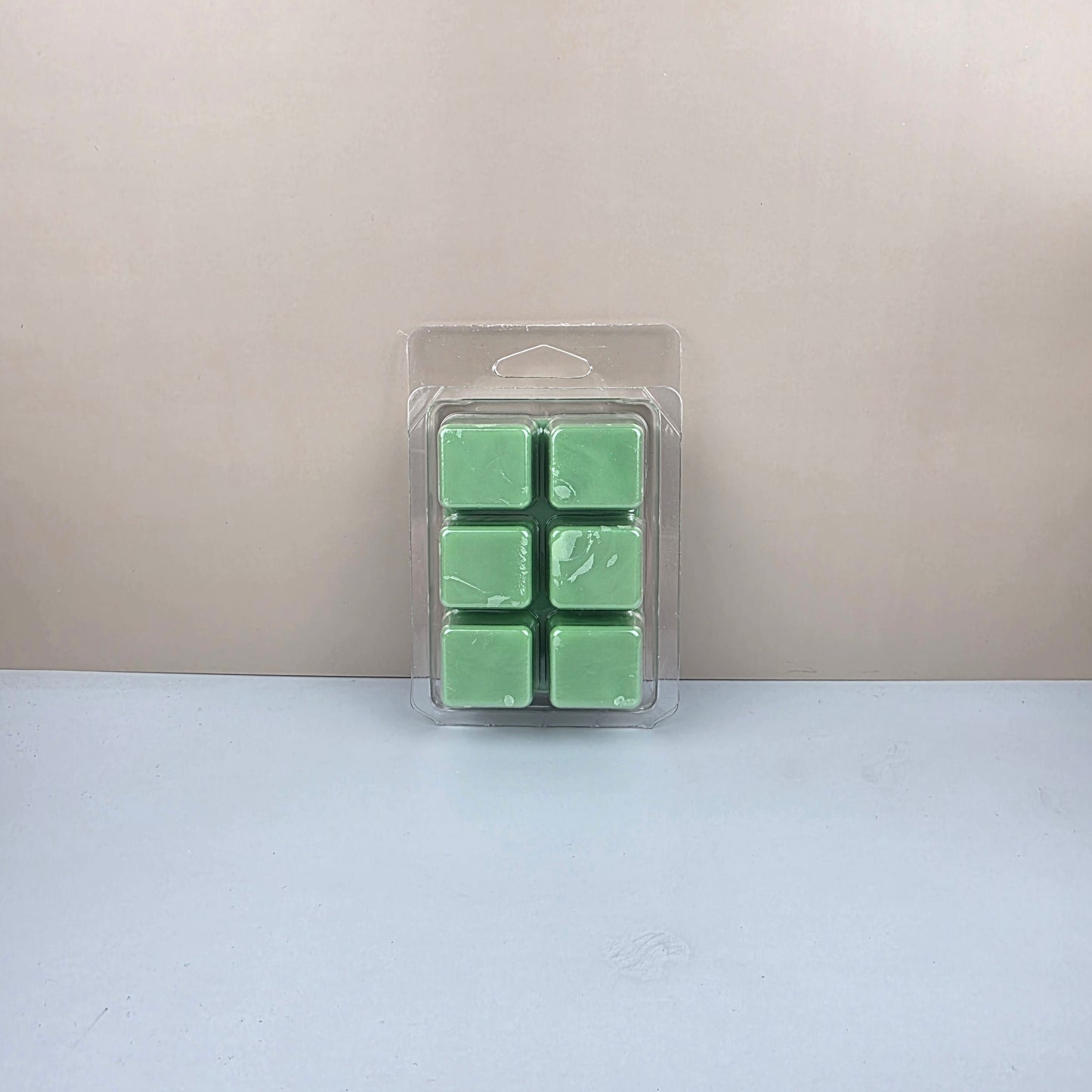 Pack of six green wax melts in a clear plastic packaging on a light gray background